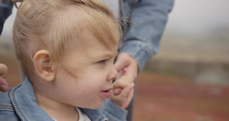A woman holds the hands of a baby