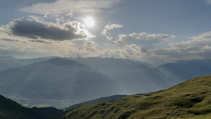 Clouds move over peaks and a valley on a sunny day