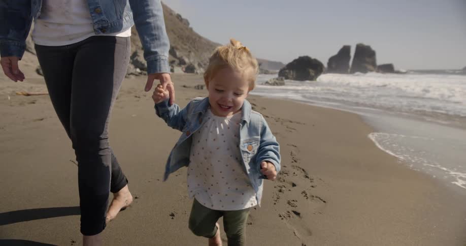 A woman is walking with her child on the beach