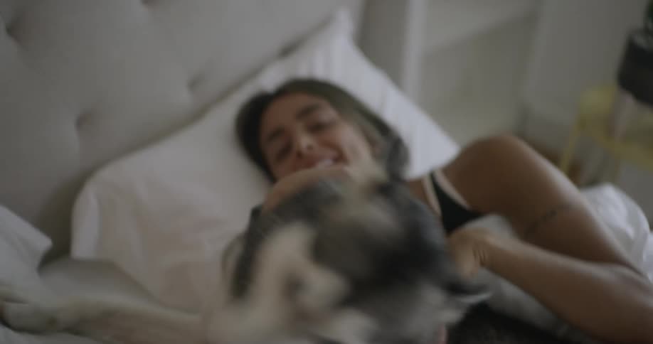 A couple pet their dog in bed