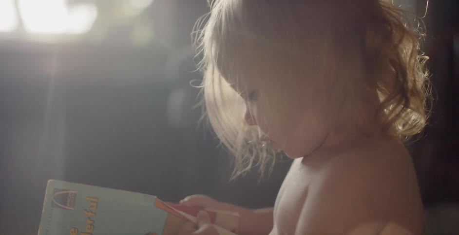 A small toddler is looking at a book