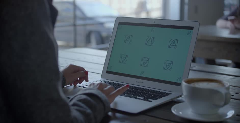 A man is using his laptop near a cup of coffee