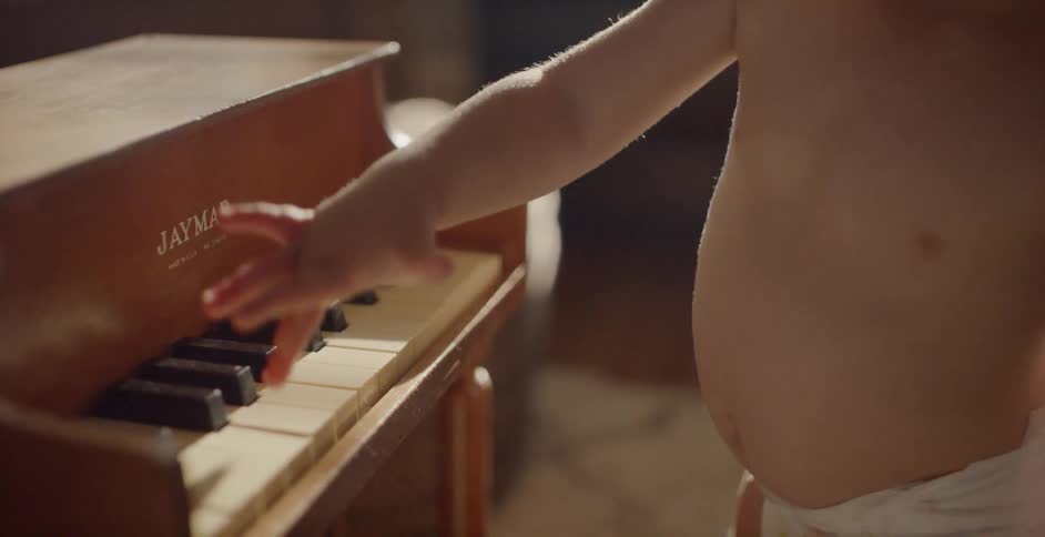 Small child hitting some keys on a small piano at sunset