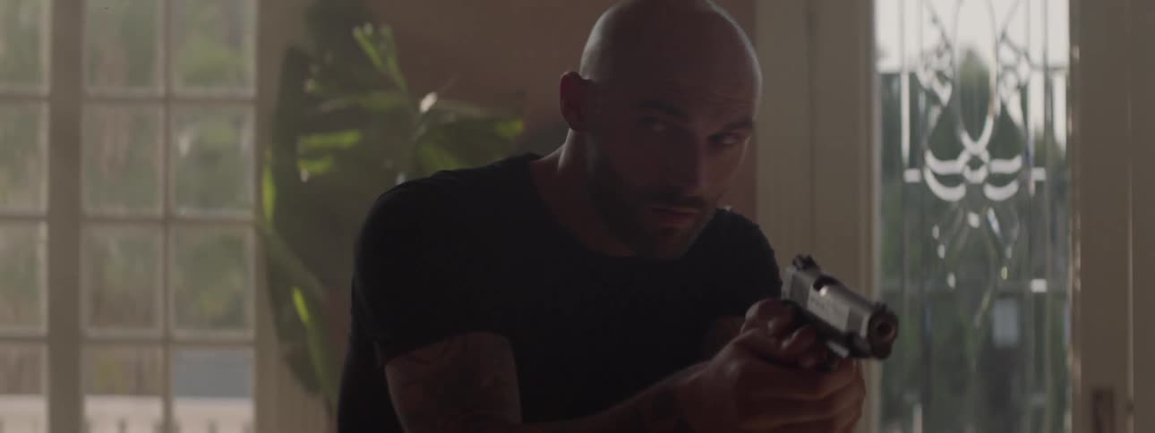 A man walks into the house aiming a gun