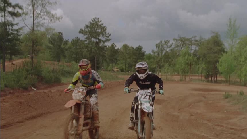 Three people are riding dirt bikes around a track