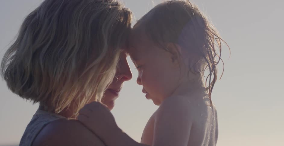 A woman and child are hugging each other outdoors