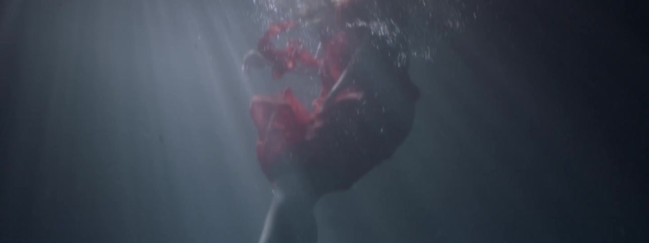 A woman swims in a lake while wearing a dress