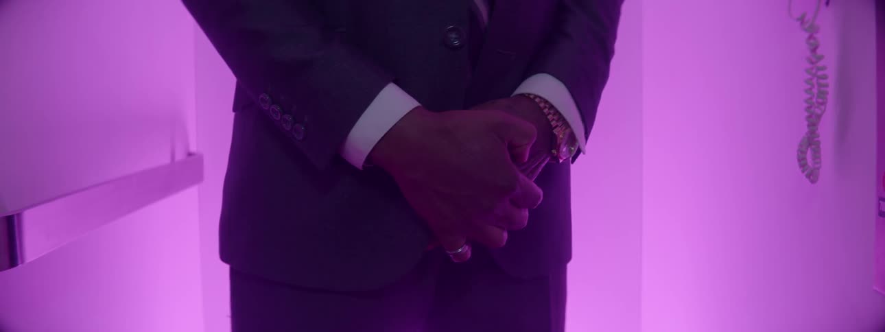 A man in a suit is standing in a purple lit room