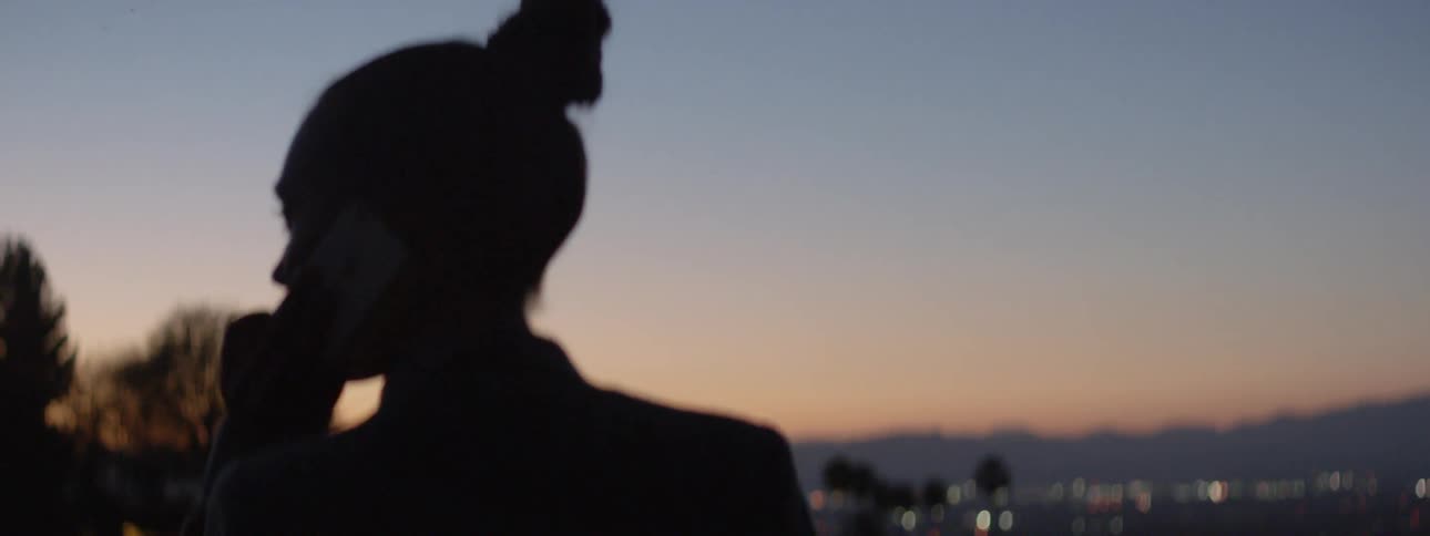 A woman talks on her phone at sunset