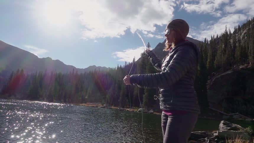 A woman fishes on a mountain lake
