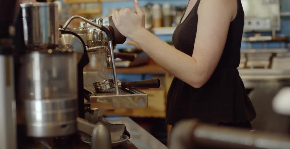 A female barista is preparing to make coffee during the day
