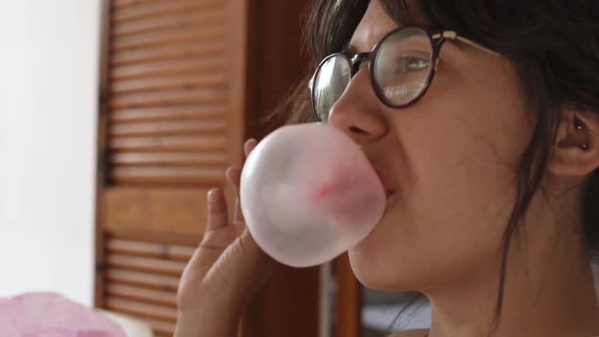 Woman wearing glasses blows a bubble