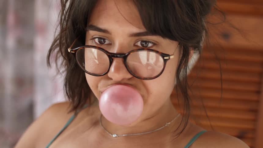Woman wearing glasses blows a bubble