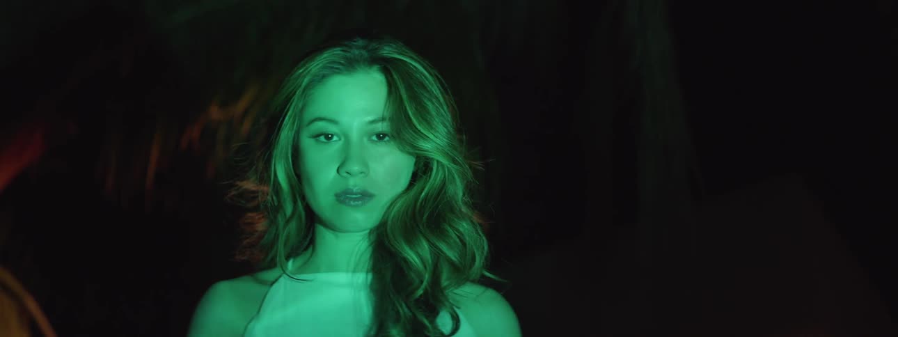 A woman is standing at night with light reflecting on her face