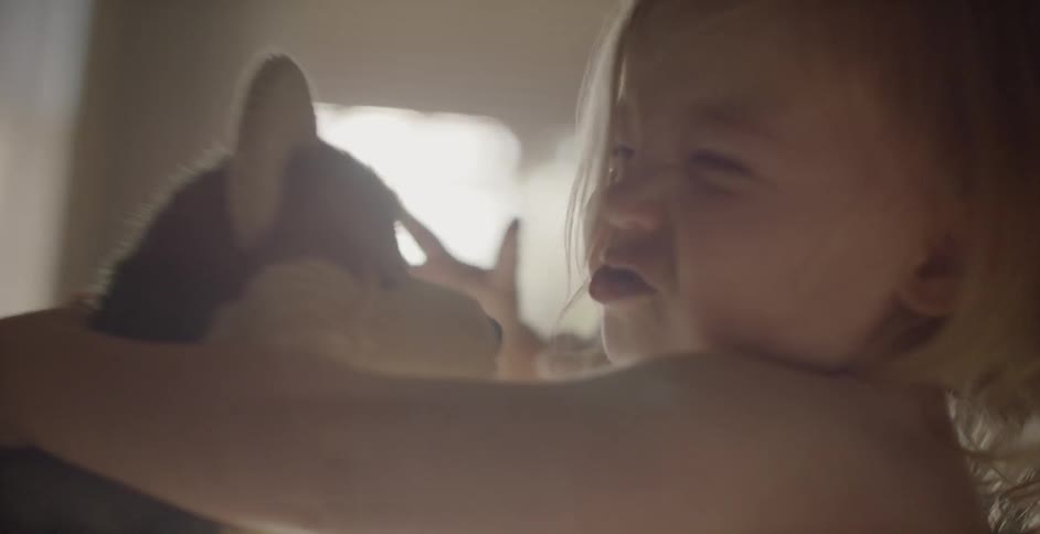 A baby grabs and hugs a stuffed dog
