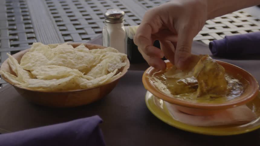 Chips and dip sit atop a table outdoors