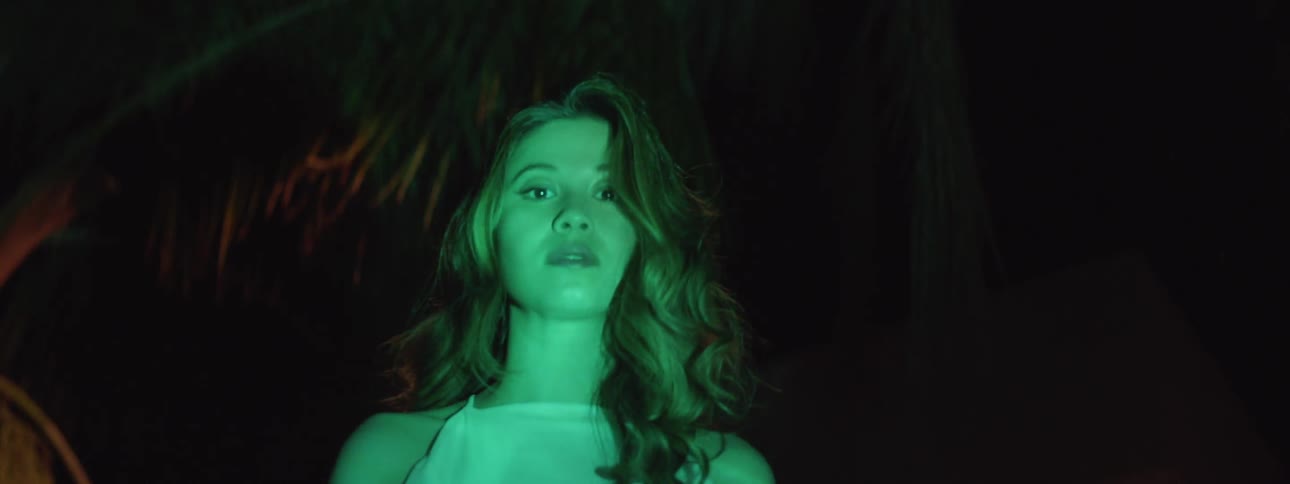 A woman is looking into the bright waters at night