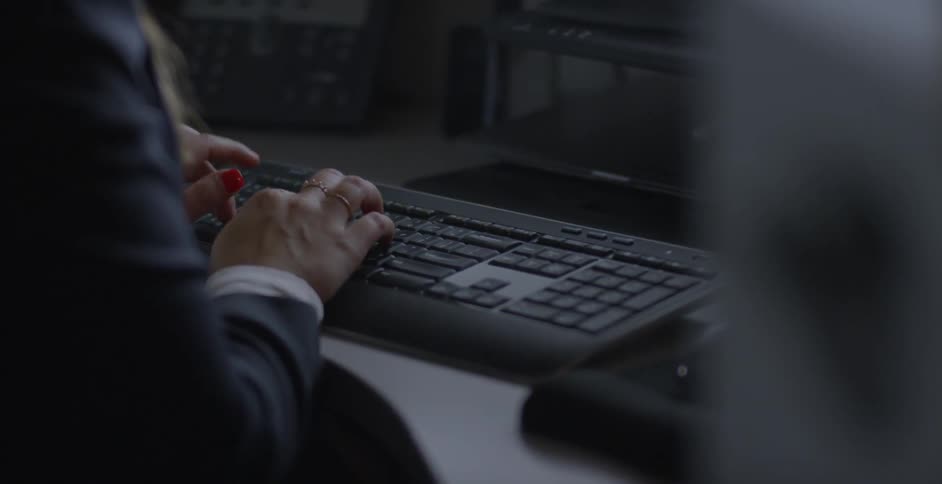 A woman is typing on a computer keyboard at a desk