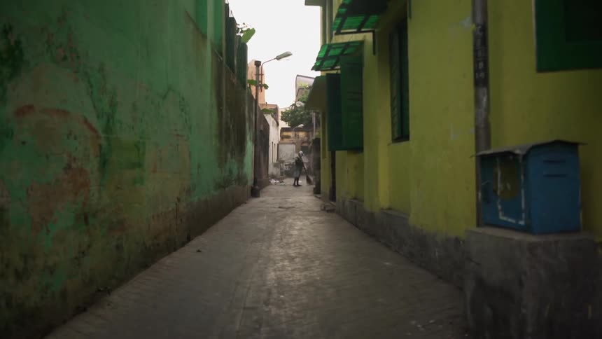 Man sweeping an alleyway between two buildings