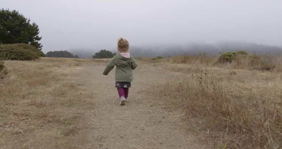 A young girl walks down a dirt trail