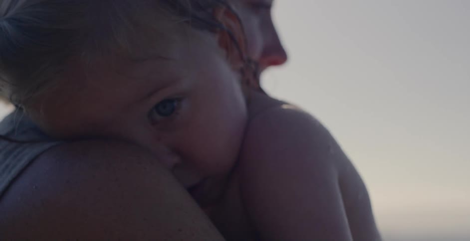 A woman holds a baby to her shoulder outside