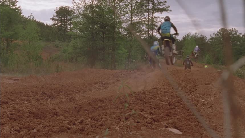 Boys on dirt bikes jump a dirt ramp