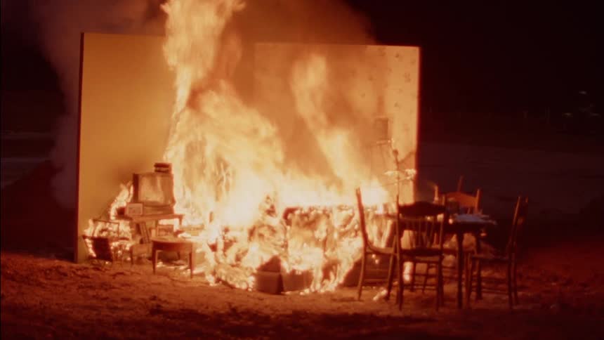 A bunch of furniture is burning outdoors at night