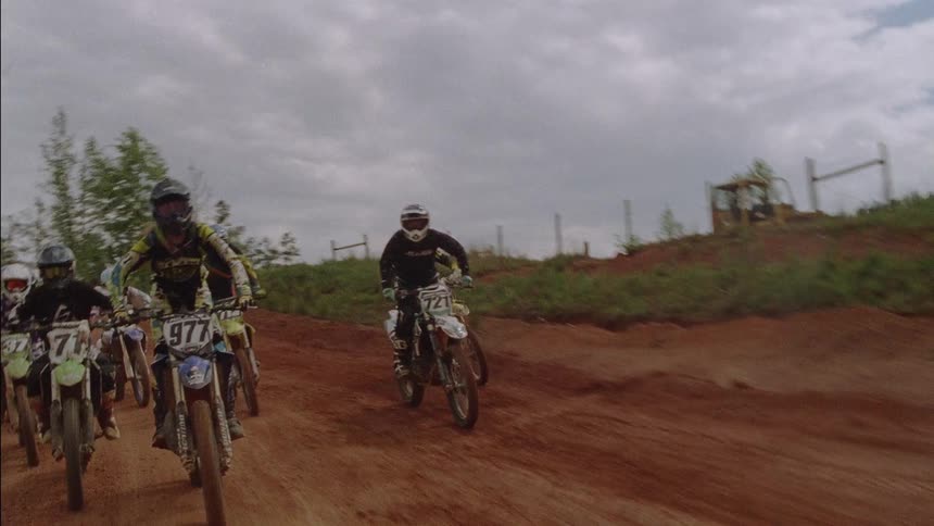 People ride dirt bikes on a rural track