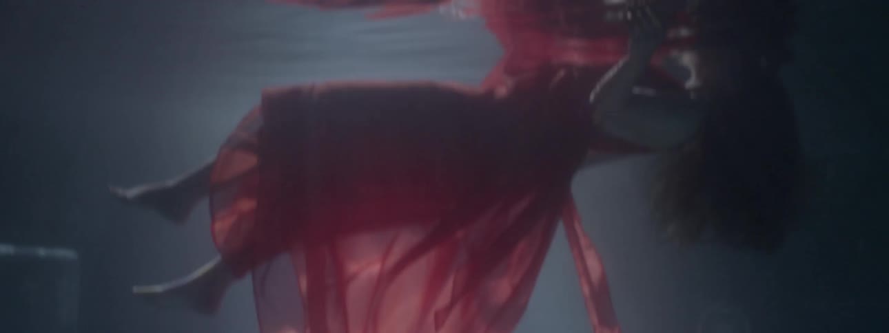 A woman in a red dress floats in water