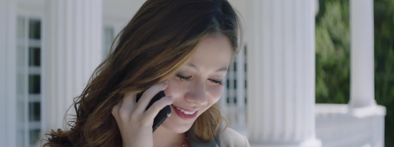 A woman talks on a phone outside then stops and stares