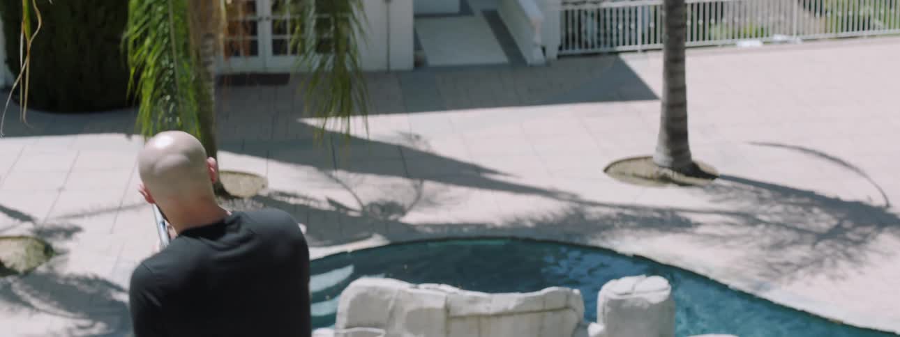 A bald man with a gun is sneaking into a home