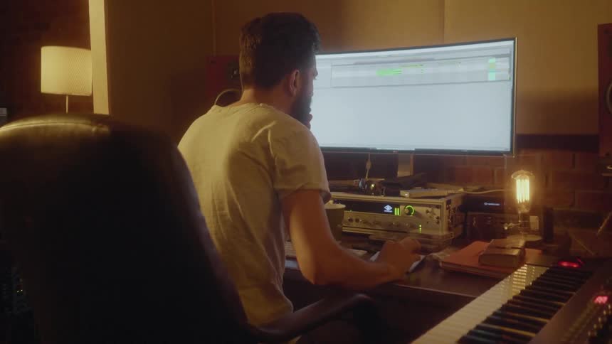 Man sits at desk making electronic music