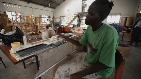 An employee works at a loom in a factory