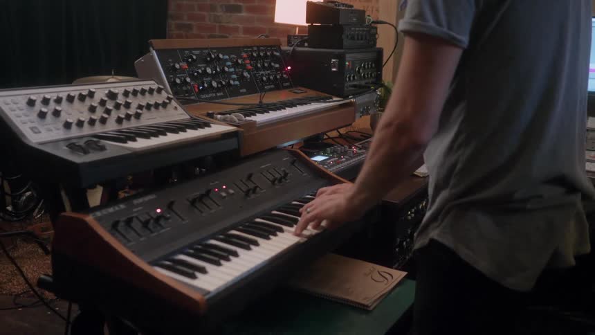 Someone is standing at a keyboard in a studio and playing a song