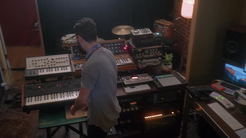 A man moves away from his computer to play on a music keyboard