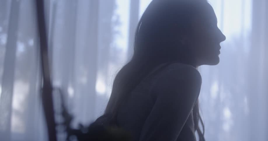 A woman sits near a window