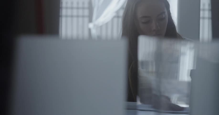 A woman is sitting at a desk looking through papers