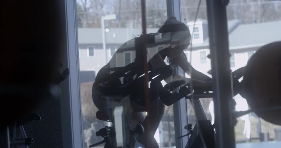 A woman is cycling as fast as she can in the gym