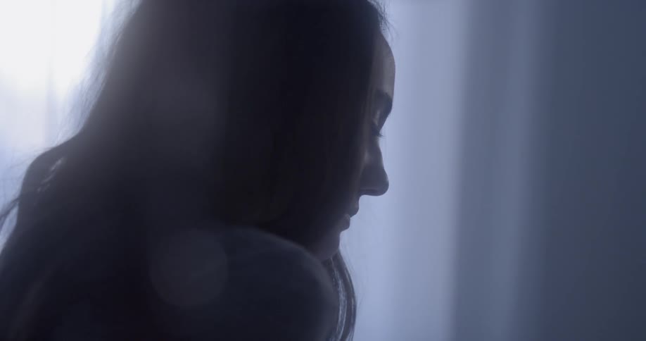 A woman looks upset in a dark room