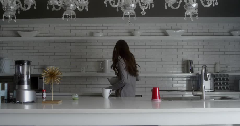 A woman is pouring from a kettle in the kitchen