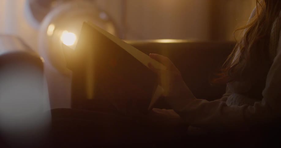 A woman is reading a book in a dimly lit room
