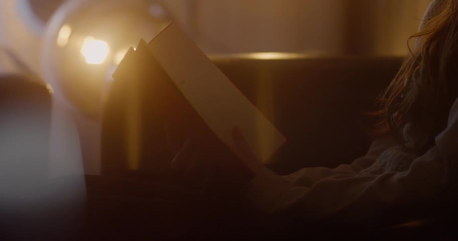Someone is reading a book in a dimly lit room