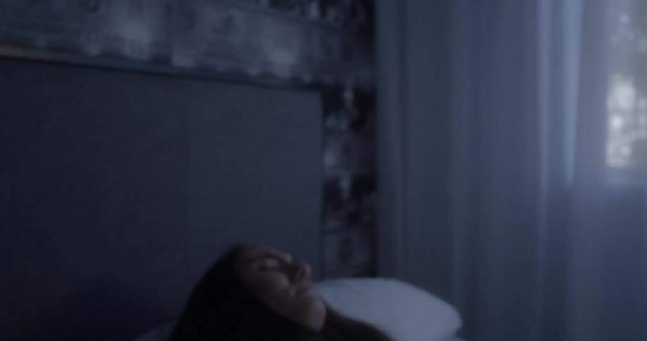 A woman wakes up and then lays back down and covers her head with a pillow