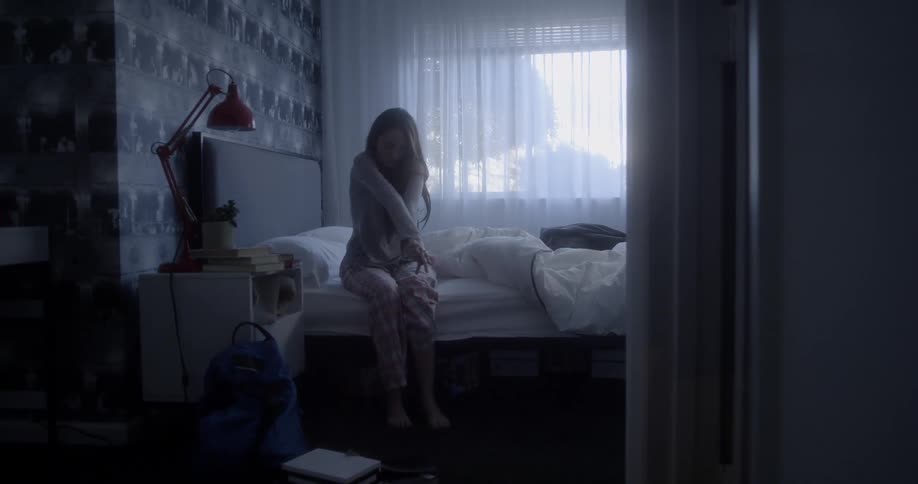 Woman sits on the edge of her bed and stretches