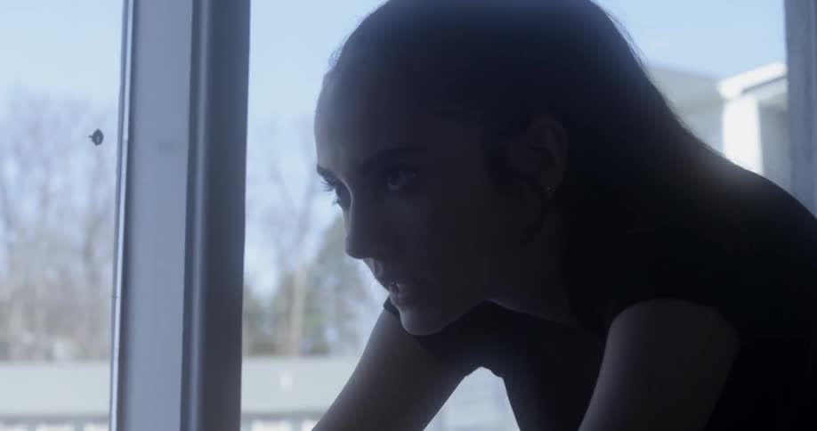 A woman is riding an exercise bike by the window