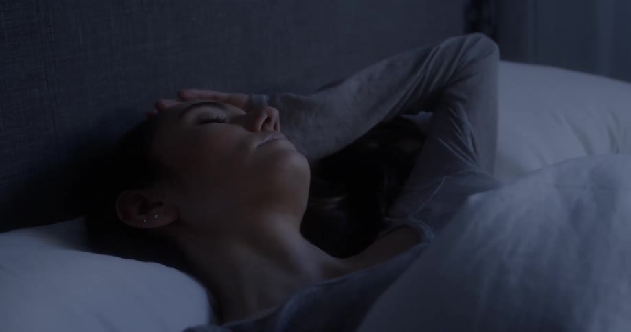 Woman lays in bed and stares into space