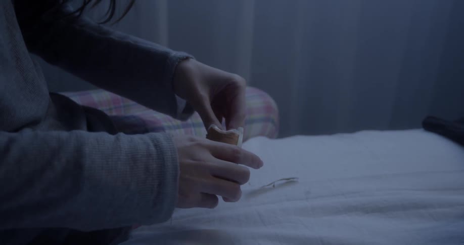 Woman sits on bed and removes a tea bag from its wrapping