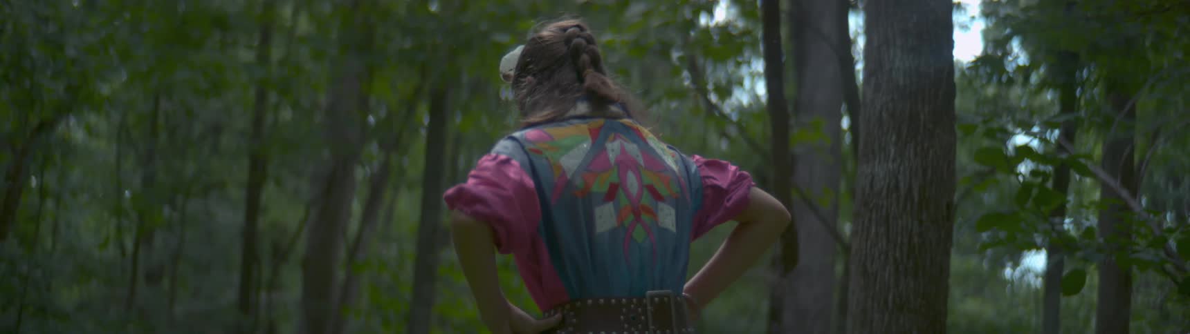 A girl is jumping up and down under the shade of trees
