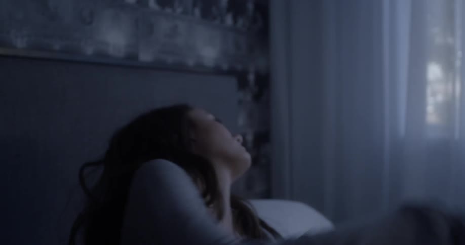 Woman rises from bed then falls back down again