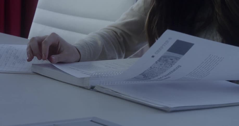 Woman sits at table and reads from a notebook